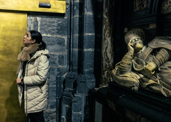 Eine Frau spaziert durch die St.-Bavo-Kathedrale und betrachtet die Messingoberfläche.