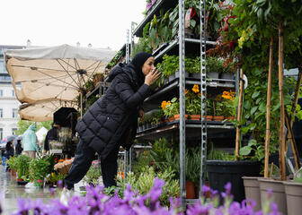 Fatina huele flores en el mercado de flores del Kouter en Gante
