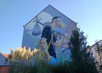 façade d'une maison avec une grande peinture murale d'un homme portant un masque