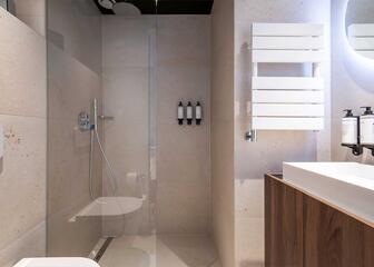 Cuarto de baño en piedra natural beige con ducha a ras de suelo, aseo y lavabo