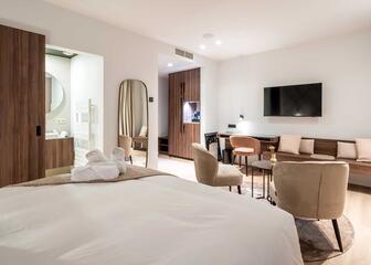 Hotelzimmer mit Doppelbett, Sitzecke, Smart-TV und Bad mit Schiebetür