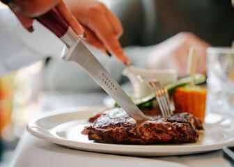 Person eats a steak at Midtown Grill Restaurant