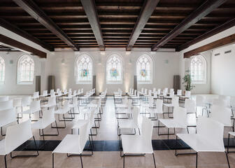 Großer Konferenzraum mit viel Licht und weißen Stühlen in mehreren Reihen