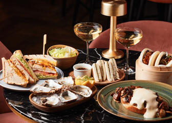 Mesa con ostras, bocadillos, tostadas con champiñones y dos copas de champán