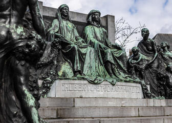 Nahaufnahme der Statue der Brüder Van Eyck. Hubert Van Eyck blättert in der Bibel, seine Palette und Pinsel liegen zu seinen Füßen. Jan Van Eyck blickt nach vorne und hält seine Palette in der Hand.