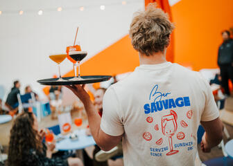 close-up of a bartender holding a tray with three cocktails