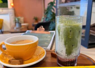 Una taza de café y un vaso de agua con menta sobre una mesa