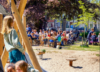 buitenfoto kinderen spelen samen op de schommel op de achtergrond terras waar mensen genieten van een hapje en drankje