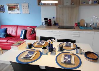 Open ruimte met zitgedeelte links en keuken met tafel rechts