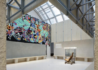 Atrium in Design Museum Gent met kleurrijk wandtapijt aan de muur.