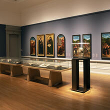museumzaal met enkele taferelen van het lam gods, vitrinekasten 