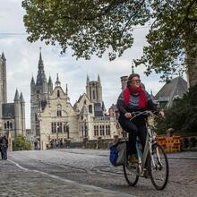 Een damesfietser van de Sint-Michielshelling met in de achtergrond de 3 torens van Gent