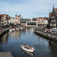 Idyllisches Bild von Graslei (rechts) und Korenlei (links) an einem sonnigen Tag. Mehrere Touristen sitzen am Wasser