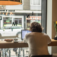Man werkt op laptop, met zicht op straat door de vitrine.