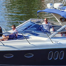 5 summerly dressed people enjoying a boat trip in a small yacht