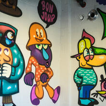 Kleurrijke animatiefiguren op een witte muur met graffiti.