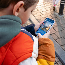 Jongen leest de volgende opdracht van de draakje Fosfor zoektocht op een smartphone