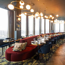 Photo taken in the dining section of Skybar with 1 big red sofa in the middle with set tables and dark blue chairs 