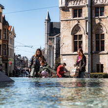 Tiany en gezin aan fontein op het Sint-Baafsplein in Gent op zonnige dag