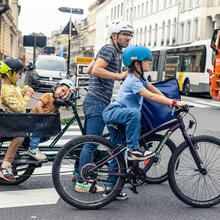 Padre cicla con bicicleta de cola de pulmón con su familia por las calles de Gante