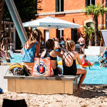 3 mensen zitten op een bankje in het zand