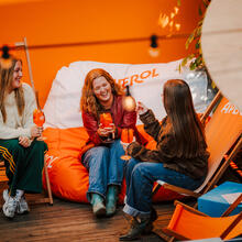 Drie vrouwen zitten op strandstoelen en genieten van een drankje