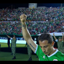 Een voetballer met opgeheven hand en een menigte die minutenlang stilte houden