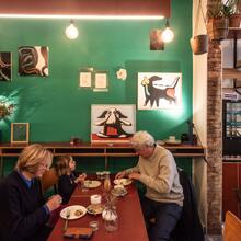 Twee volwassenen en een kind zitten aan een tafel koffie te drinken