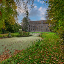 zicht op kloostertuin met bomen en grasperk. Blauwe hemel zonnige dag. Het klooster op de achtergrond