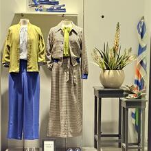 Shop window display featuring mannequins and clothing in yellow and blue